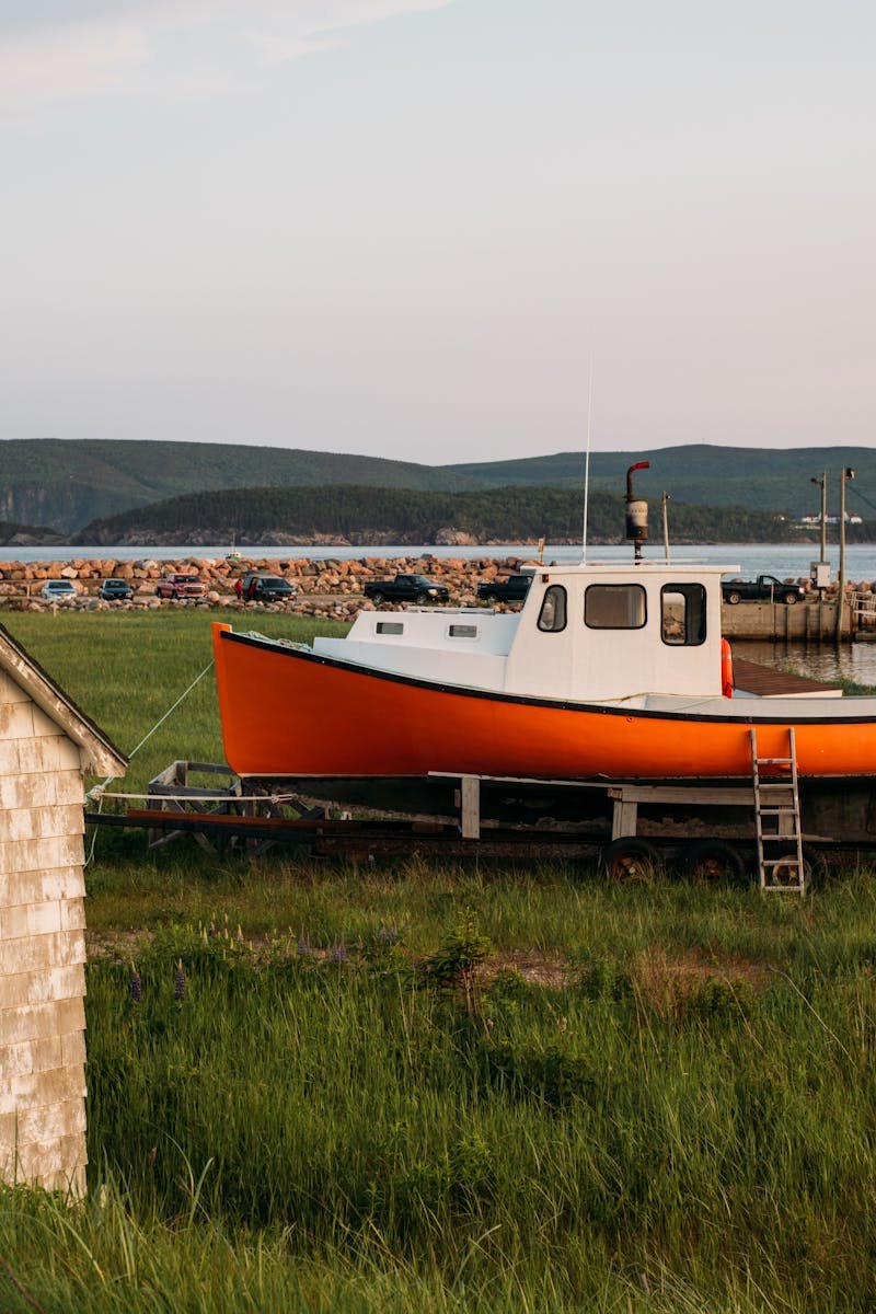 Fishing boat on land by a scenic harbor in Nova Scotia during sunset.