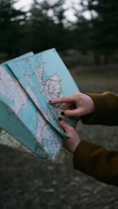 Close-up of hands pointing at a map outdoors, suggesting exploration or travel planning.